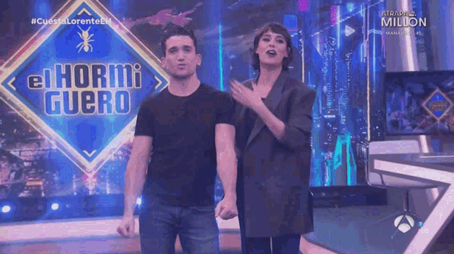 a man and a woman stand in front of a sign that says el hormiguero