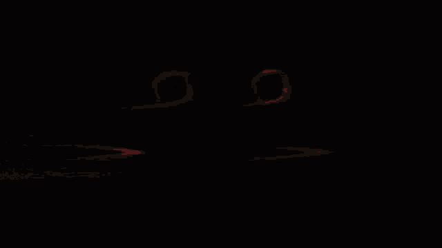 a red smiley face with circles around the eyes is glowing in the dark