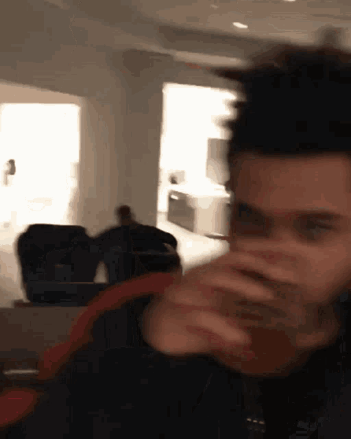 a blurry picture of a man drinking from a glass in a room .