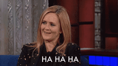 a woman is laughing while sitting on a couch with the words `` ha ha ha '' written on her face .
