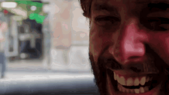 a close up of a man 's face with a beard smiling