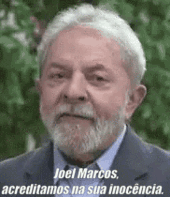 a man with a beard and gray hair is wearing a suit and tie and has a quote on his face .