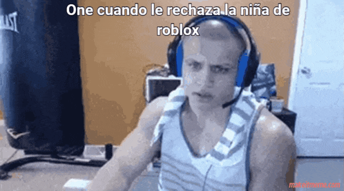 a man wearing headphones and a tank top is sitting in front of a computer .