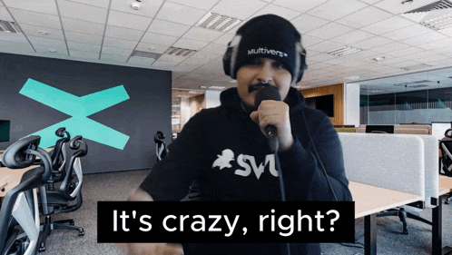 a man singing into a microphone with the words " it 's crazy right " behind him