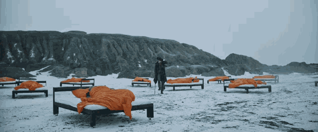 a man stands in front of a row of beds with orange blankets on them