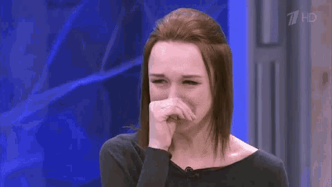 a woman is covering her mouth with her hand while crying on a television show .