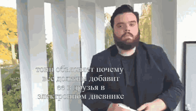 a man with a beard is holding a cell phone in front of a foreign language advertisement