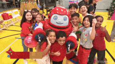a group of children posing for a picture with a red robot