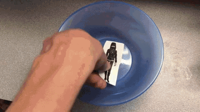 a person is putting a picture of a woman in a bowl of water .