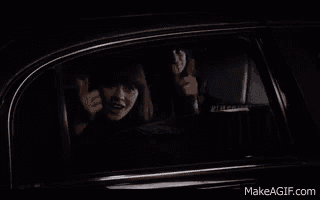 a woman is sitting in a car looking out the window .