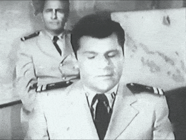 a man in a suit and tie stands in front of two other men