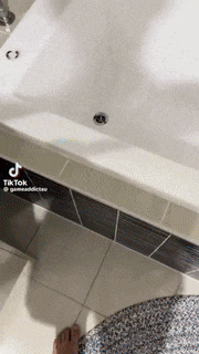 a person standing next to a bathtub in a bathroom