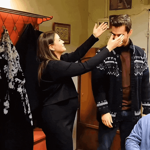 a woman wipes a man 's eyes with her hand