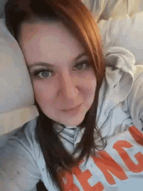 a woman with red hair is laying in bed with her head on a pillow and wearing a shirt that says ' denim '