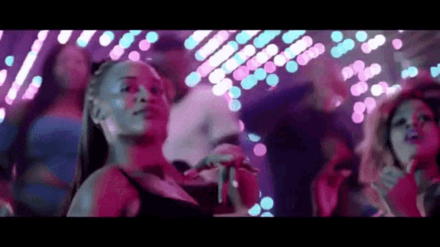 a woman is dancing in front of a crowd of people at a nightclub .