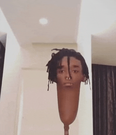 a man with dreadlocks and a nose ring is standing in a room with a prosthetic leg in front of him .