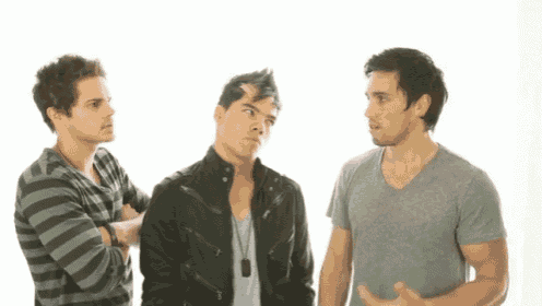 three men standing next to each other with one wearing a striped shirt and a black jacket