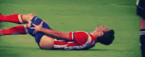 a soccer player is laying on the ground with a knee injury during a game .