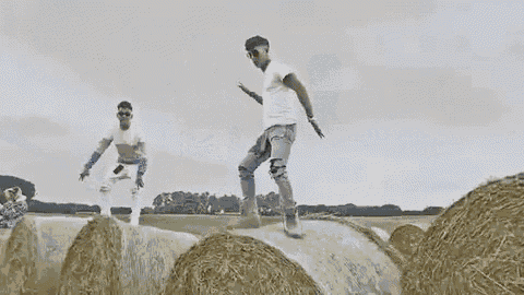 a man is standing on top of a hay bale in a field .
