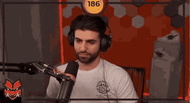 a man wearing headphones is sitting in front of a microphone in a studio .