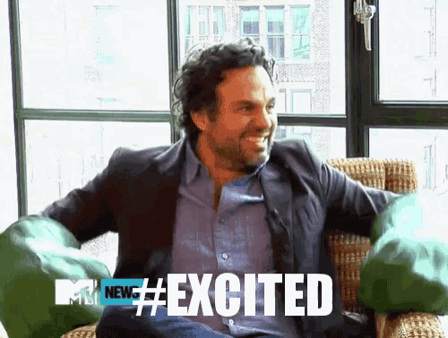 a man is sitting in a chair with his arms outstretched and the words excited on the screen
