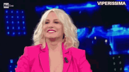 a woman in a pink jacket is smiling in front of a blue background that says viperissima