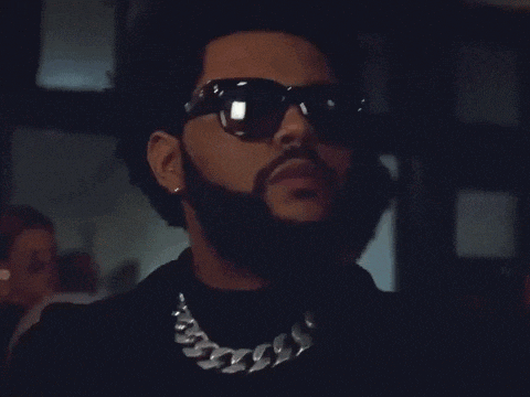 a man with a beard and sunglasses is standing in a crowded room .