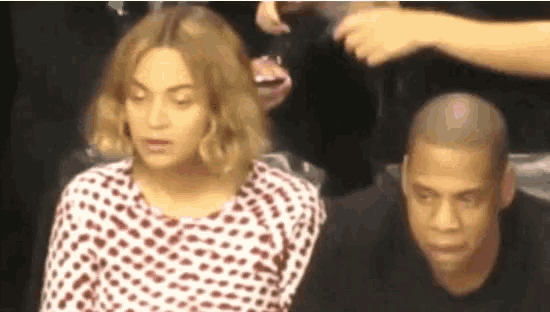 a man and a woman are sitting next to each other . the woman is wearing a white and red polka dot shirt .
