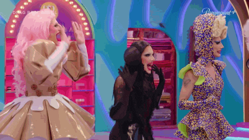 three drag queens are standing next to each other on a stage with paramount written on the screen