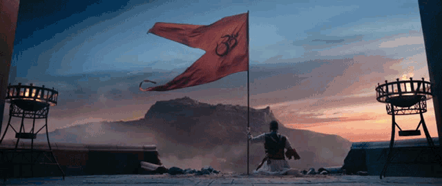 a man kneeling in front of a red flag with an om symbol