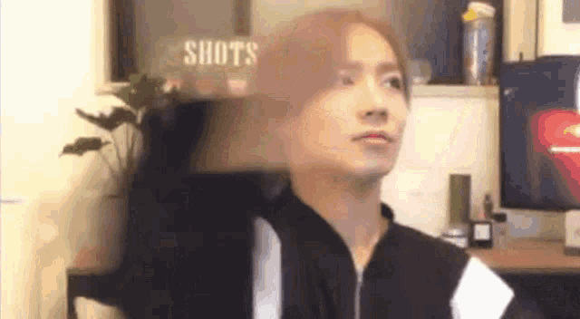 a blurry picture of a man standing in front of a sign that says `` shots '' .