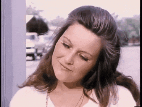 a close up of a woman 's face with long hair and a white shirt .