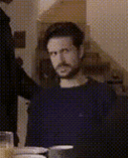 a man with a beard is sitting at a table with a glass of orange juice in front of him .