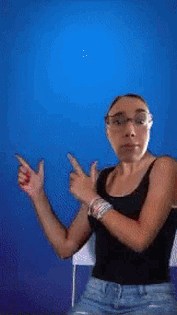 a woman wearing glasses and a black tank top is pointing at something
