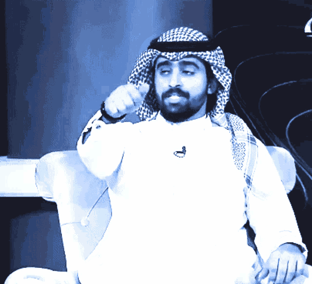 a man with a beard wearing a white shirt and a head scarf