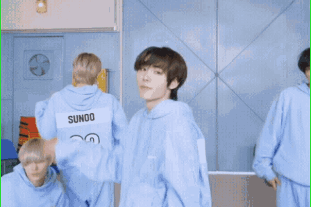 a boy in a blue hoodie is standing in a room