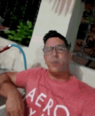 a man wearing glasses and a red aeropostale shirt smoking a hookah .