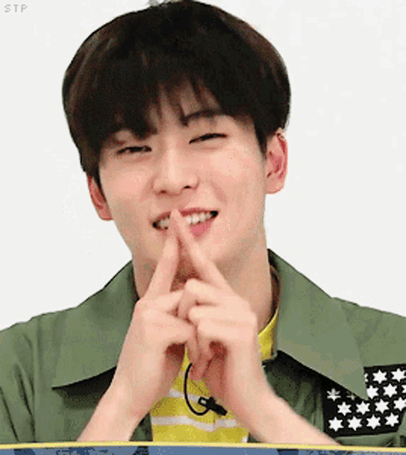 a young man is making a heart shape with his fingers and smiling