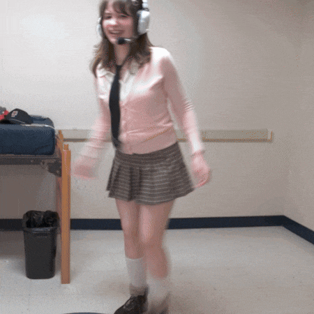 a woman wearing headphones and a pink sweater is standing in a room