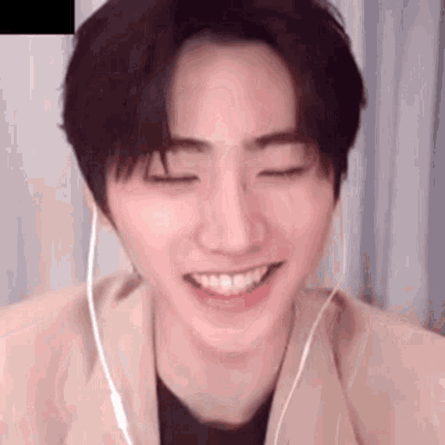 a young man wearing headphones is smiling with his eyes closed and his mouth open .