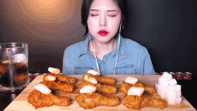 a woman wearing headphones is eating chicken on a wooden cutting board