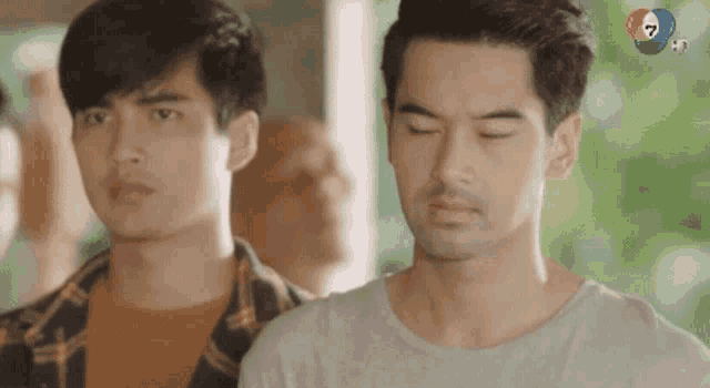 two men are standing next to each other with their eyes closed . one of the men is wearing a plaid shirt .