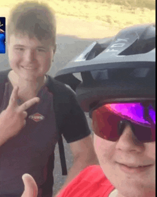 a man wearing a helmet and sunglasses is giving a peace sign next to a woman wearing sunglasses .