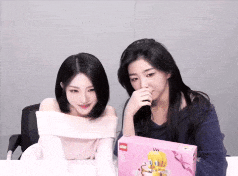 two girls are looking at a pink box with a tweety bird on it
