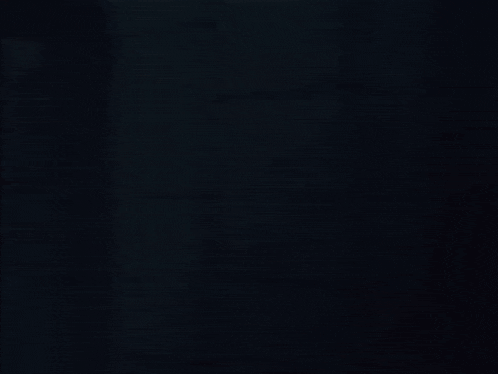 a woman in a red dress and black tie stands in a dark room