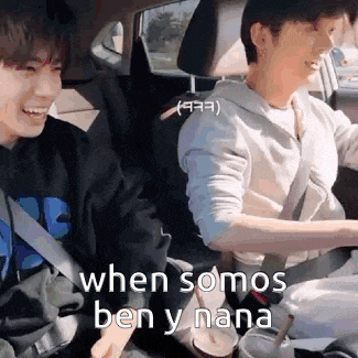 two young men are sitting in the back seat of a car laughing .