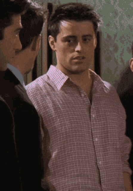 a man in a plaid shirt stands between two other men in suits