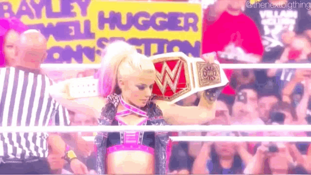 a woman in a wrestling ring is holding a wrestling championship belt .