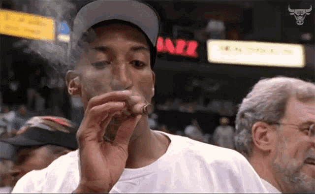a man is smoking a cigar in front of a bulls sign
