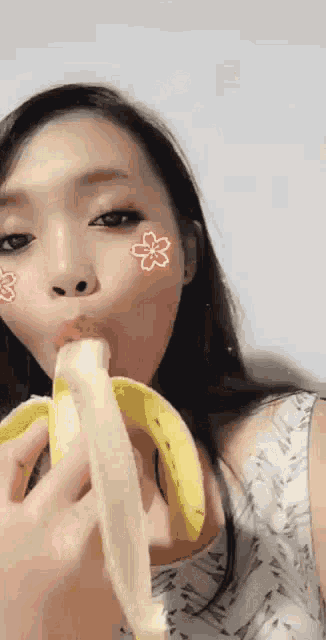 a woman is eating a banana with a flower on her face